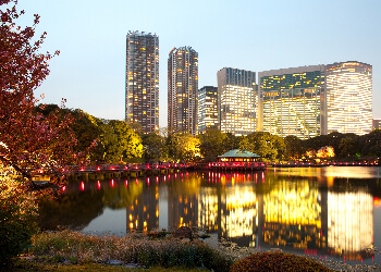 Hamarikyu-Garten in Tokyo bei Abenddämmerung mit Wasser und Hochhäusern.